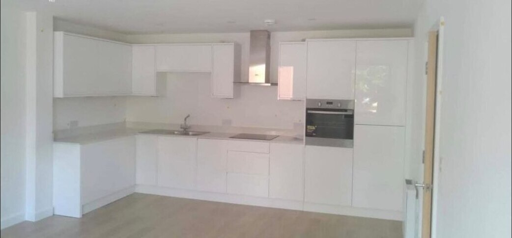 Completed L-shaped kitchen with white gloss handleless cabinetry and integrated appliances.