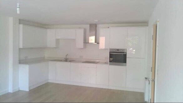 Portrait view of a residential kitchen installation with handleless cabinetry and fitted appliances.