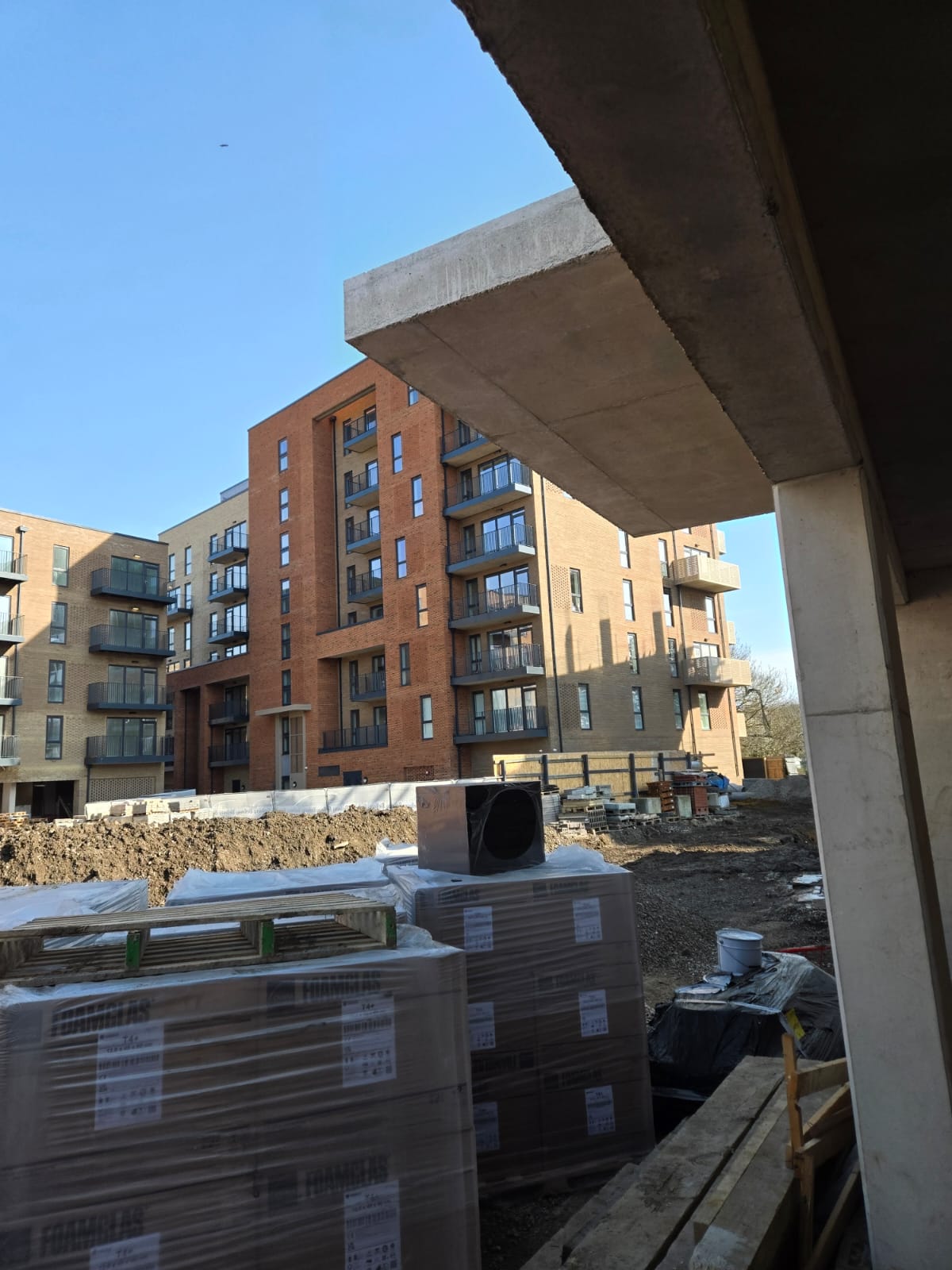 Wrapped furniture pallets staged outside a newly built apartment block before installation across multiple units.