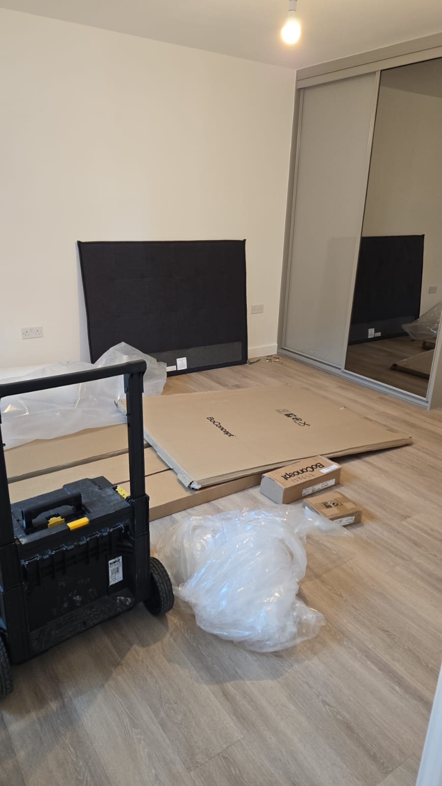 Bedroom furniture mid-installation with wardrobe doors fitted and bed components prepared for assembly.