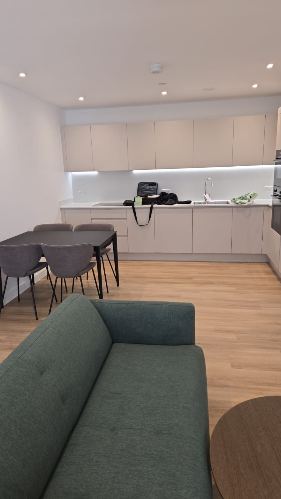 Finished open-plan apartment with fitted kitchen, dining set, and seating installed by Smart Corpo.